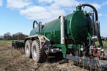 Fototapeta premium Modernes Güllefass mit angebauter Scheibenegge für schnelles Einarbeiten der Gülle in den Boden.