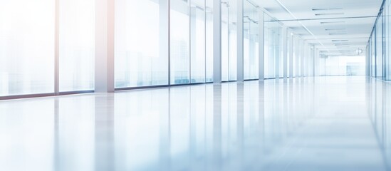 This image showcases a long hallway in a business office with numerous glass walls. The corridor is empty, with a white room visible in the background, creating a modern and spacious atmosphere.