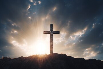 Cross on the top of a hill with dramatic sky and sun rays