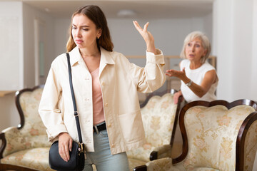 Domestic quarrel between elderly mother and adult daughter in the living room