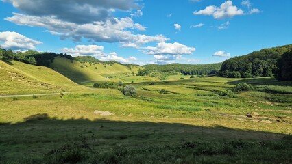 Naklejka premium Nature landscape in Romania with green meadows, hills, forests and blue sky, on a beautiful summer day.