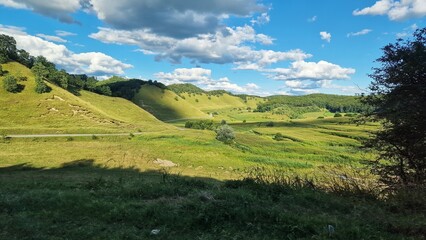 Nature landscape in Romania with green meadows, hills, forests and blue sky, on a beautiful summer day.