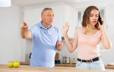 Adult daughter father scolding and yelling at her in home kitchen