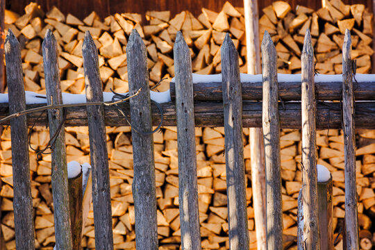 sustainable rural energy background in winter. blurred stacked firewood behind the wooden fence