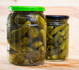 Image of glass jar with pickled cucumbers on wooden background