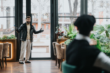 A welcoming man opens his arms in greeting inside a stylish cafe, illustrating warm hospitality or...