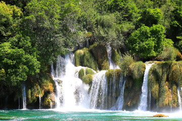 Fototapeta na wymiar cascade waterfall among large stones in Krka Landscape Park, Croatia in spring or summer. The big beautiful Croatian waterfalls, mountains and nature.