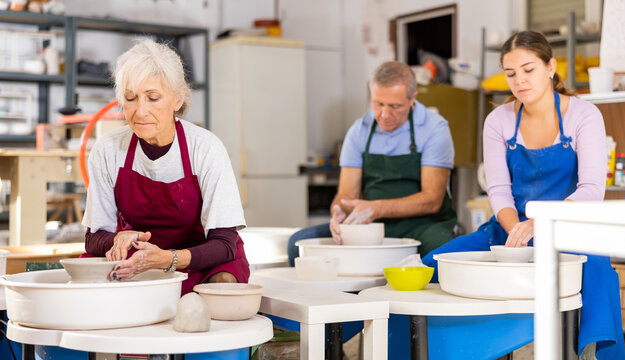 during class in pottery workshop, lady works on potter's wheel