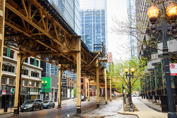 Elevated rail tracks over a street  lined with modern high rise office buildings in Chicago Loop downtown district on a cloudy spring day