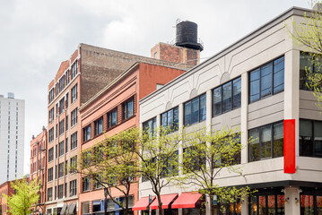 Traditional and modern buildings with retail space on the ground floor along a tree lined street in a downtown district on a cloudy spring day