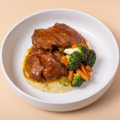 Close-up plate of beef ribs in barbecue sauce with vegetables and mashed potatoes angle view