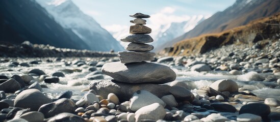 A stack of rocks rests on the river shore, surrounded by water, under a sky filled with clouds. The mountainous landscape provides a natural and tranquil setting for travelers to enjoy