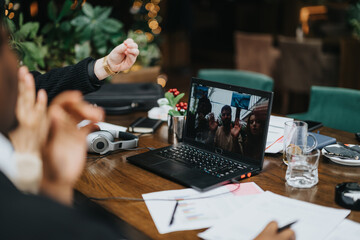 Multiethnic professionals collaborate over a virtual meeting in a restaurant setting, showcasing teamwork and modern work dynamics.