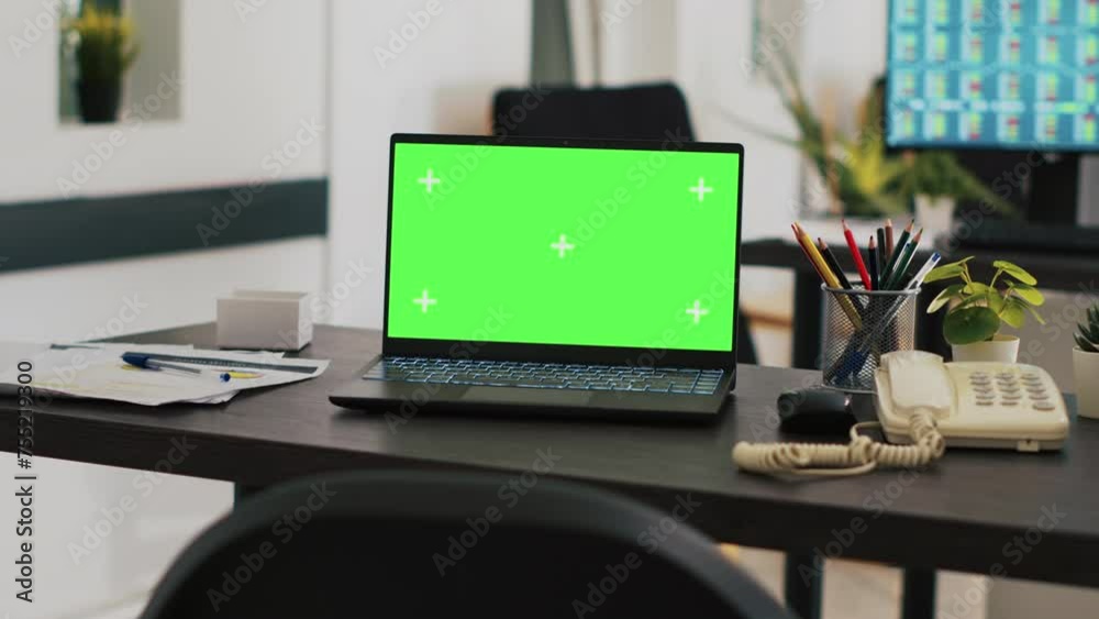 Poster office with green screen laptop on desk and monitor in background with stock exchange listings. mock