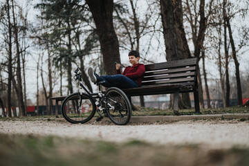 A joyful young boy takes a break on a bench in the park with his bicycle laid beside him, capturing a moment of active childhood.