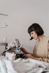 A woman in her mid-thirties is engrossed in sewing, creating textiles in her workshop.