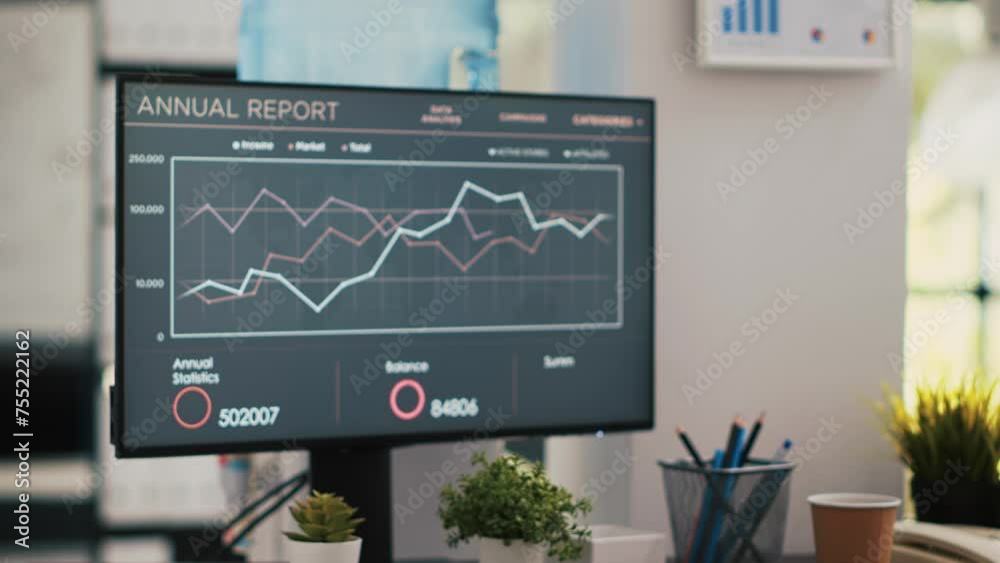 Poster business graphs and figures on computer monitor left open in empty workspace. economic annual report