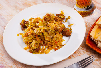 Appetizing cabbage stewed with pork meat on white plate. High quality photo