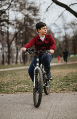 A joyful young boy riding his bicycle through a verdant city park, exemplifying the pleasures of childhood and outdoor activities.