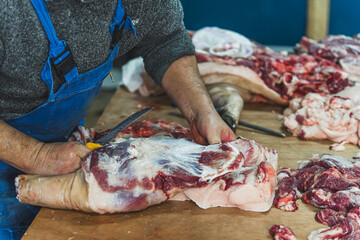 old butcher working at the shop, cutting and preparing the meat for sale. High quality photo