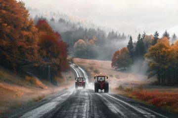 Foto auf Acrylglas Two vehicles are traversing an asphalt road under a rainy sky. The tractors tires grip the wet road surface, passing by trees in the natural landscape © RichWolf