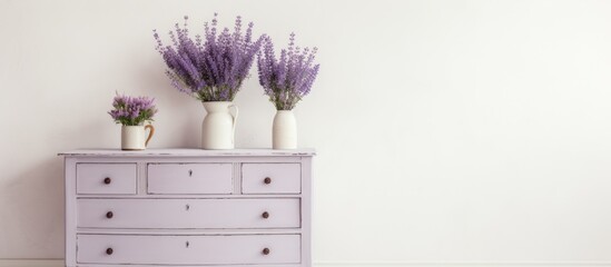 A white dresser with three decorative vases placed on top of it, set against a light wall background. The vases add a touch of elegance and color to the dresser.