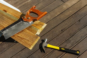 A manual carpentry saw on some wooden boards next to a hammer