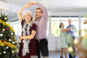 Couple of adult man and elderly woman dancing waltz in studio..