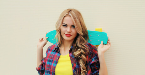 Stylish young blonde woman posing with skateboard on city street © rohappy