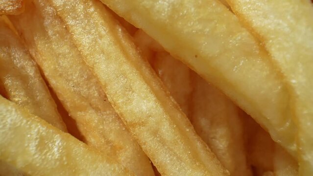 Golden strips of potatoes, fried to crispy perfection, French fries tantalize taste buds with their salty crunchiness, a beloved classic worldwide. Carbohydrate concept. French fries background. 4K.
