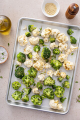 Broccoli and cauliflower florets on a sheet pan ready to be roasted - 755236517