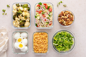 Healthy vegetarian meal prep with boiled eggs, roasted vegetables, cooked lentils, couscous salad and nuts
