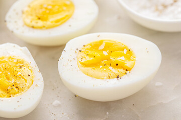Boiled eggs peeled and cut in half with salt and pepper - 755240183