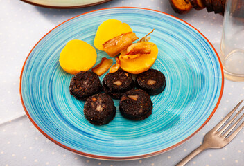 Traditional Spanish blood sausage slices with rice served with baked potatoes..