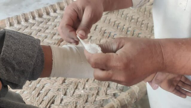 Traditional Pakistani Hakeem Treating Boy's Broken Arm with Herbal Remedy