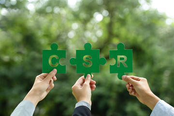  CSR (Corporate social responsibility) concept. Hand of business people holding a piece of a jigsaw puzzle with the word CSR for giving back to the community and responsible consumption.Save the world - obrazy, fototapety, plakaty