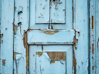 an old door with peeling paint because it is old and not cared for
