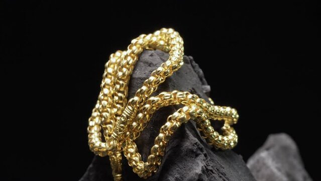 Closeup shot of gold necklaces on charcoal with rotating
