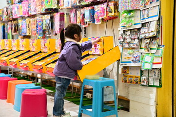 Taiwan - Jan 23, 2024: A girl tries to win prizes on a pinball machine. The pinball machine is a popular game at night markets, and players can win small toys, snacks, or stationery by scoring points.