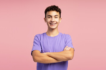 Portrait of confident smiling boy with dental braces wearing purple t shirt with crossed arms