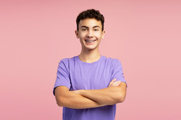 Portrait of confident smiling boy with dental braces wearing purple t shirt with crossed arms