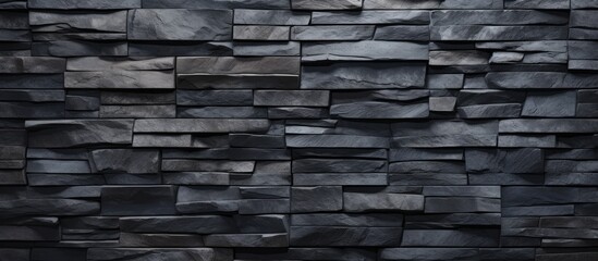 A detailed view of a dark grey stone wall made up of textured bricks, showcasing the intricate patterns and surfaces of the individual stones.