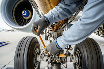 Aircraft Mechanic at Work Inspecting Landing Gear Close-up View - obrazy, fototapety, plakaty