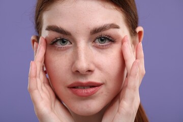 Portrait of beautiful woman with freckles on purple background, closeup