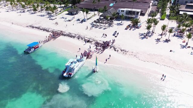 People board a tourist catamaran to embark on a tour of tropical islands with exotic beaches and turquoise lagoon, Dominican Republic, Caribbean Sea. A bird's eye view.