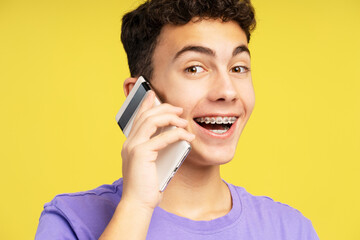 Smiling, attractive boy, teenager laughing talking on mobile phone, answering call