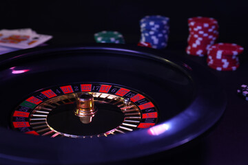 Roulette wheel, playing cards and chips on table, closeup. Casino game