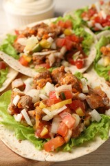 Delicious tacos with vegetables and meat on table, closeup