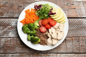 Balanced diet and healthy foods. Plate with different delicious products on wooden table, top view