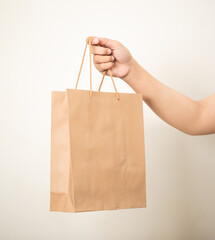 hand holding a shopping paper bag against a white isolated background